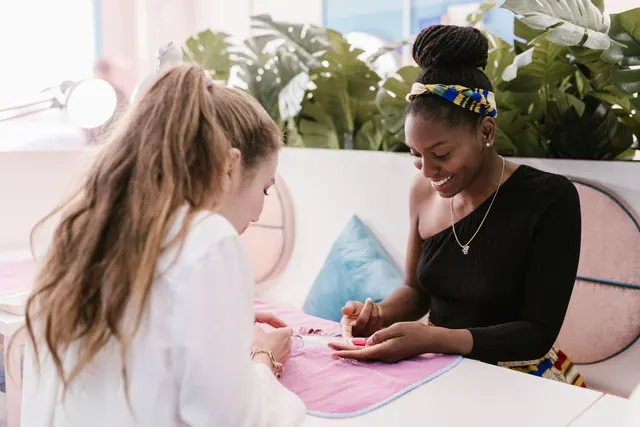 Two women enjoying a manicure session in a bright nail salon setting.