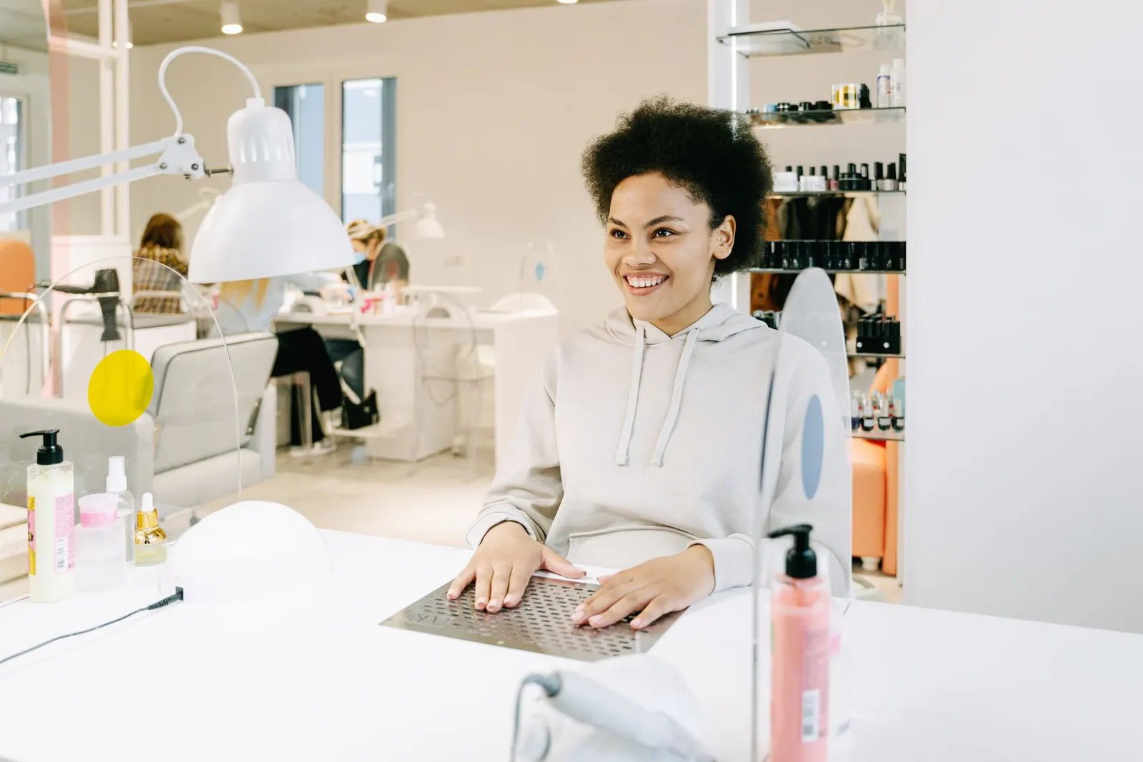 Smiling woman with afro hair having a manicure at a modern nail salon.